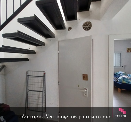 קיר גבס עם חור עגול ליד מדרגות שחורות